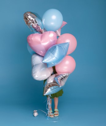 dziewczyna stoi za dużym zestawem balonów napompowanych helem
