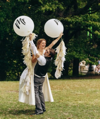 weselne zdjęcie pary młodej na korym trzymają w rekach białe balony z napisem "Mr" "Mrs"