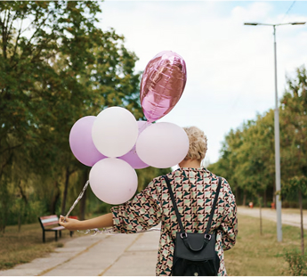 kobieta z plecakiem idąca z zestawem balonów