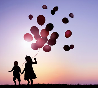 dwoje dzieci z balonami na tle zachodu słońca